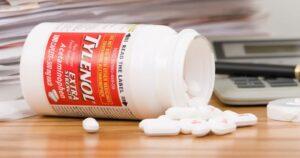 Tylenol spilled on a desk covered in lawsuits.