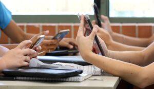 Photo of kids in school absorbed in social media on their mobile devices.