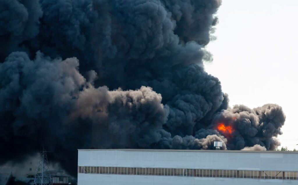 Black plumes of smoke rising from a factory fire.