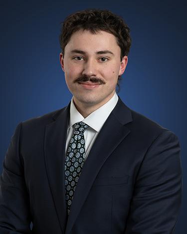 Dylan Walczak, wearing a suit and tie against a blue background