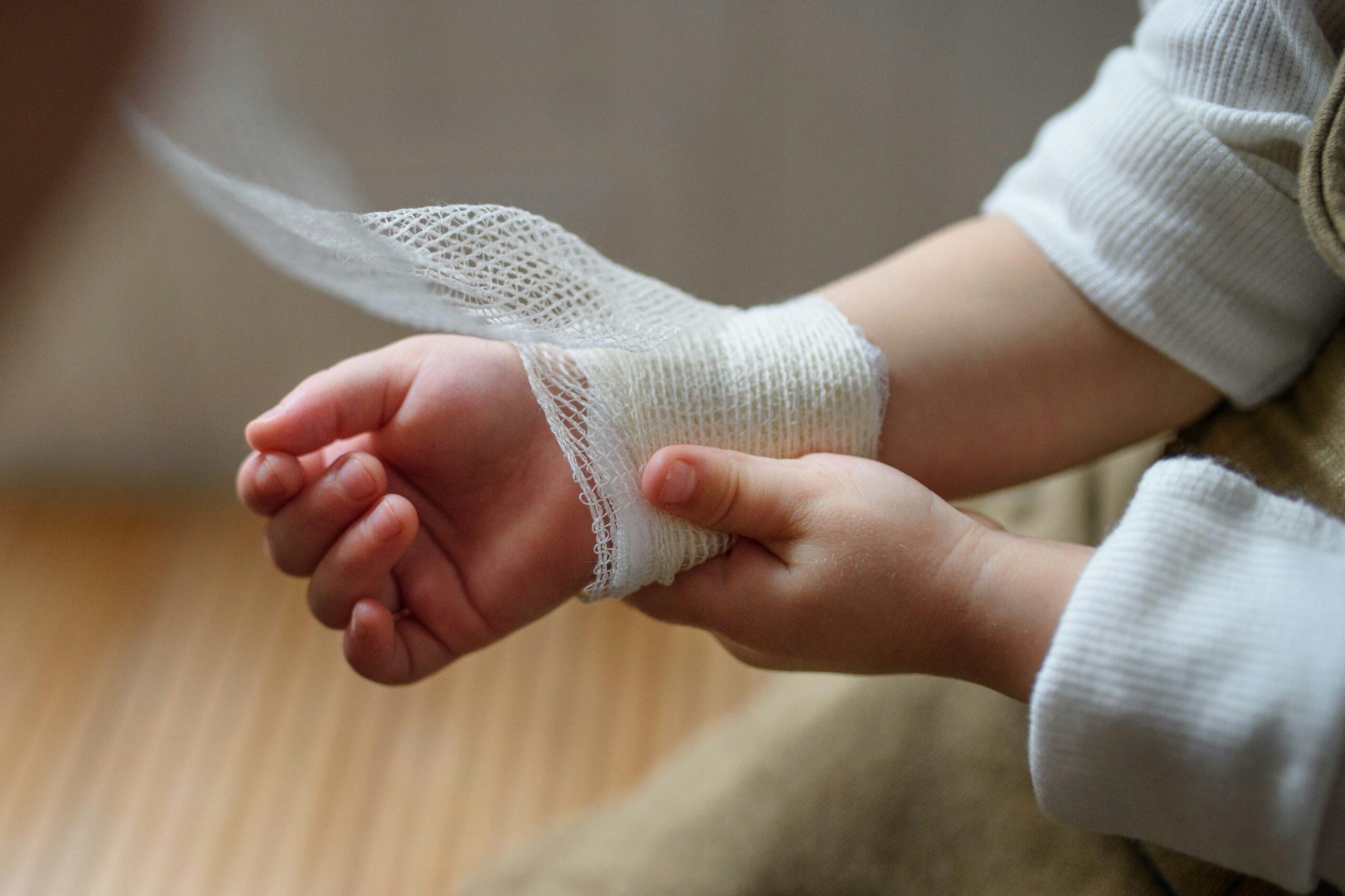 Close-up of a hands wrapping a bandage around their injured wrist, showing care and tenderness during first aid.