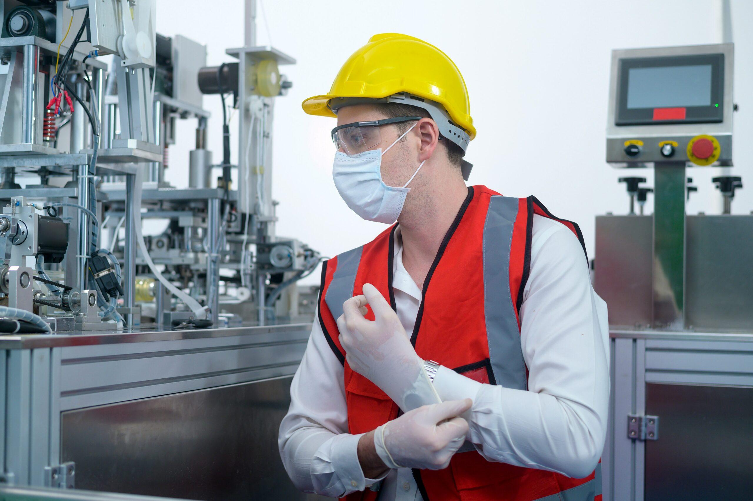 A man in a mask and gloves works in a factory, ensuring safety and hygiene in the production environment.