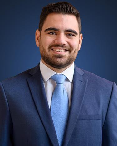 Image of Alan Reyderman wearing a suit and tie in front of a blue background