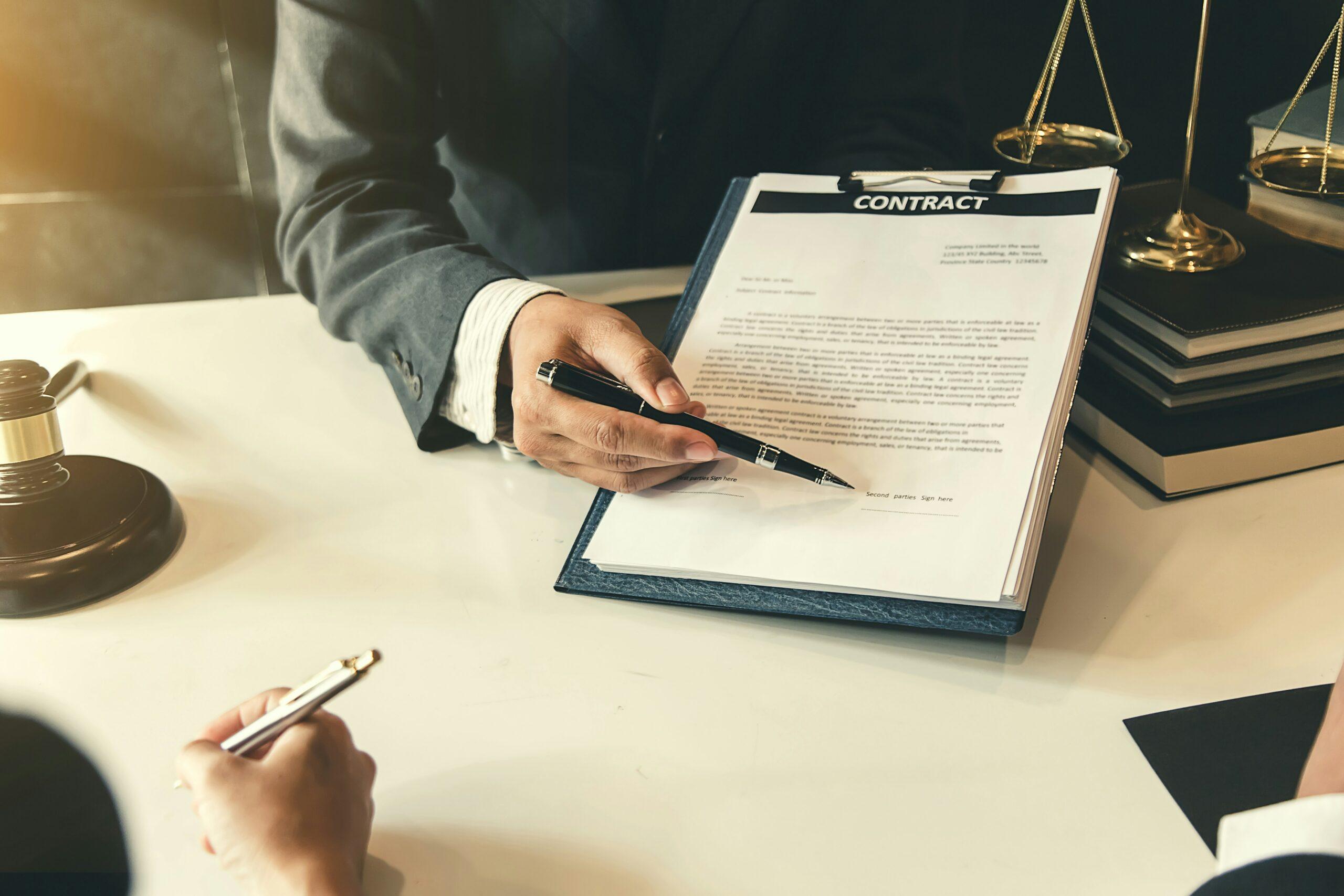 A lawyer and client signing a contract at a desk, with documents and a pen visible in the scene.