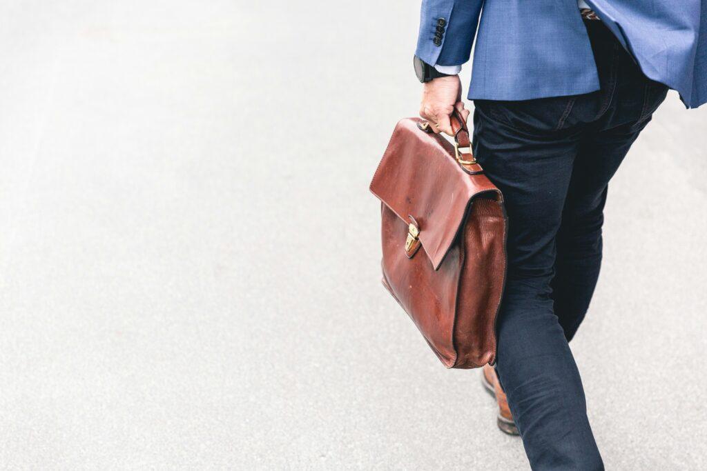 A man in a suit and tie walks down the street, carrying a briefcase.