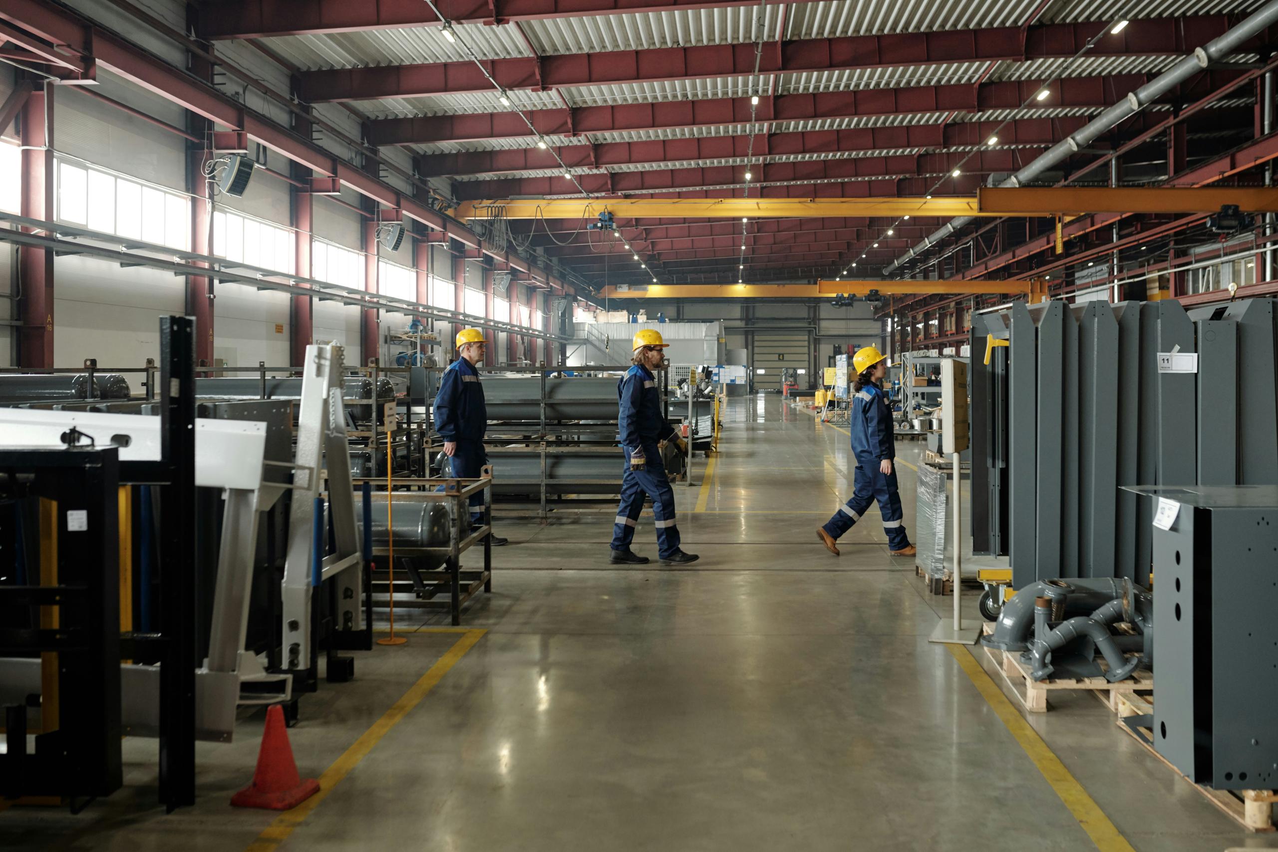 Workers operating machinery in an industrial factory, focused on production tasks in a busy environment.