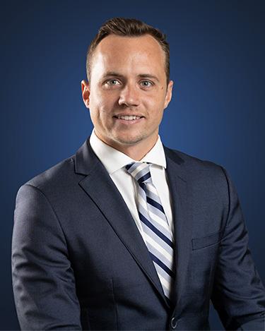 Kaio Carter, wearing a dark suit in front of a dark blue background