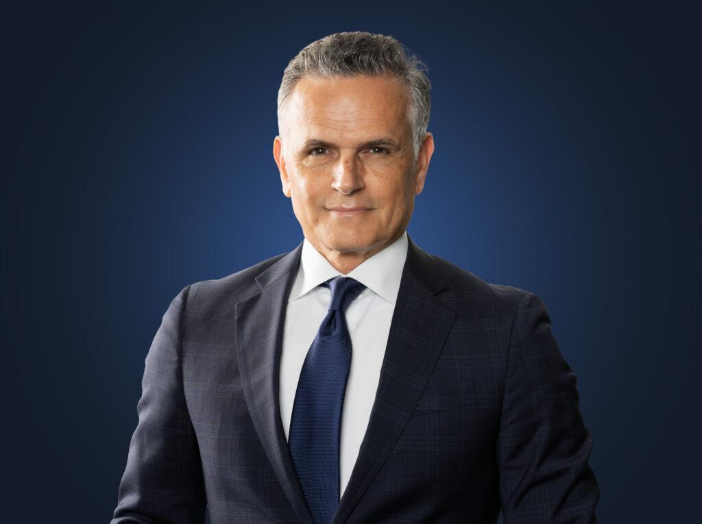 Mark Leonetti, wearing a dark suit in front of a blue background