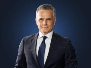 Mark Leonetti, wearing a dark suit in front of a blue background