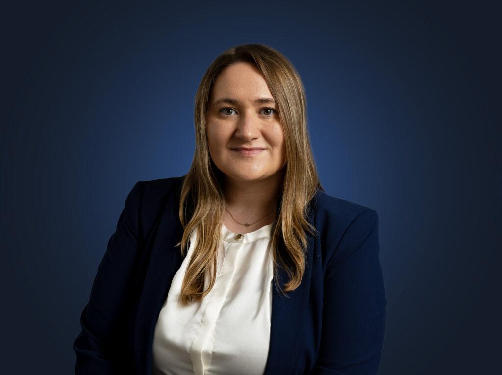 Mary Hains sits in front of a dark blue background