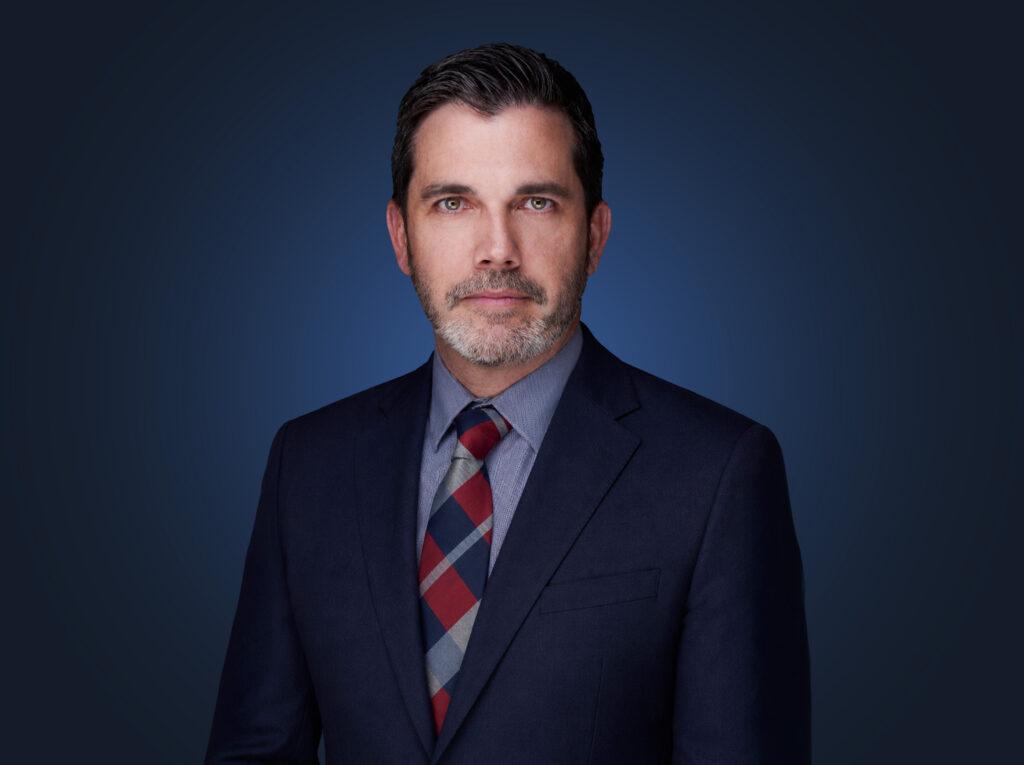 Attorney Gabe Spooner in front of a dark blue background