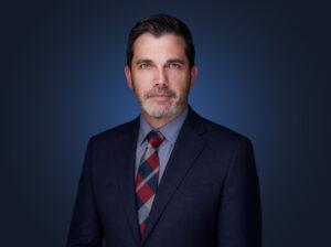 Attorney Gabe Spooner in front of a dark blue background