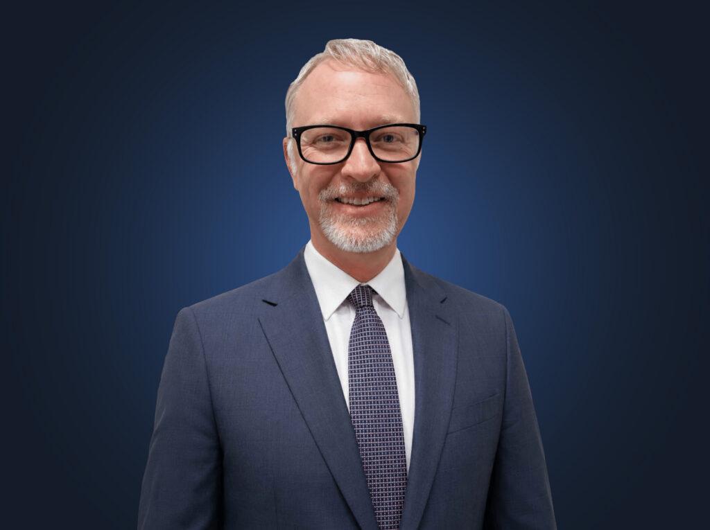Attorney Jonathan Elms, wearing a dark suit in front of a dark blue background