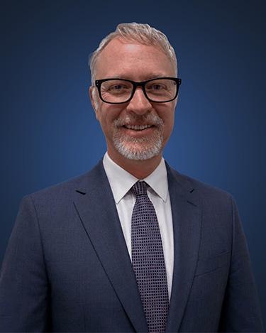 Attorney Jonathan Elms, wearing a dark suit in front of a dark blue background