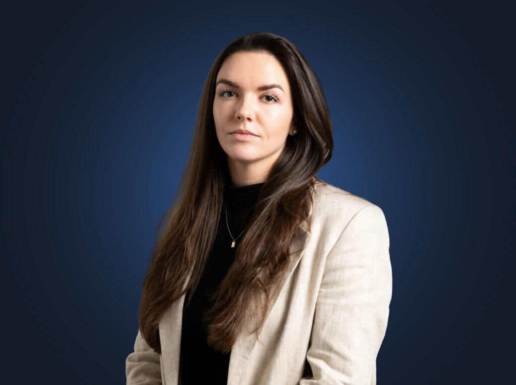 Attorney Kate Hurley wears a light suit in front of a dark blue background
