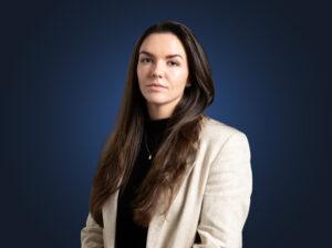 Attorney Kate Hurley wears a light suit in front of a dark blue background