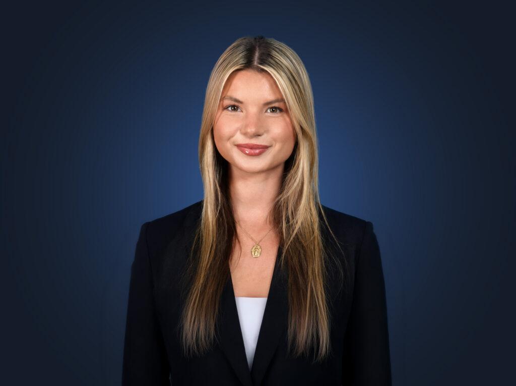Attorney Olivia Scholl wears a dark suit in front of a dark blue background